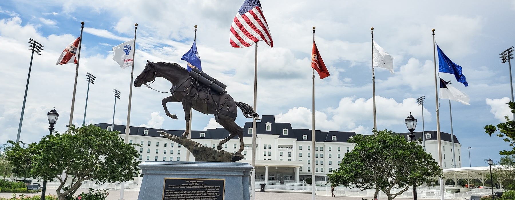 a statue in front of flagpoles and a large building